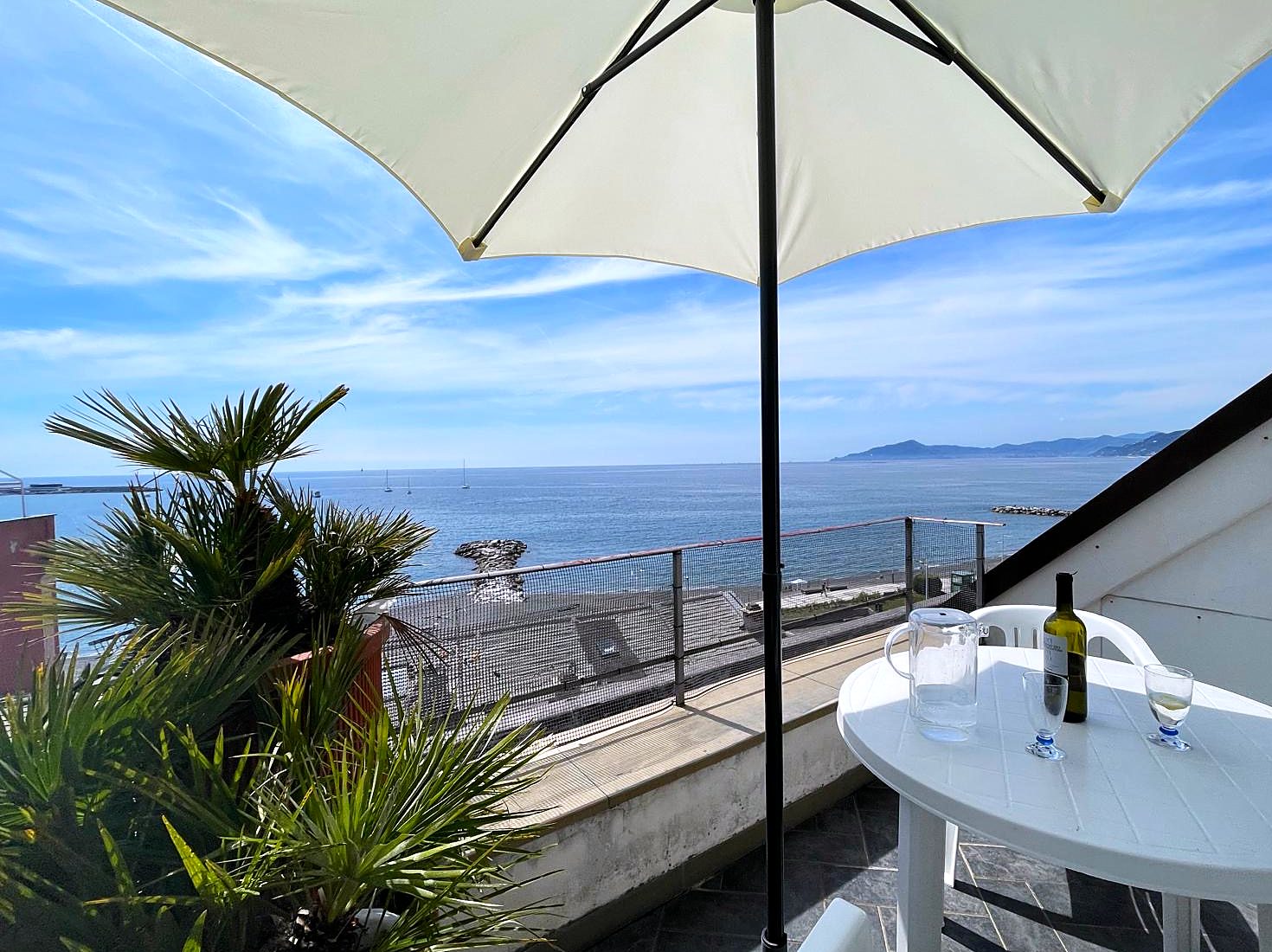 Il terrazzo dell'attico con tavolo, ombrellone e vista sul mare e sul promontorio di Portofino